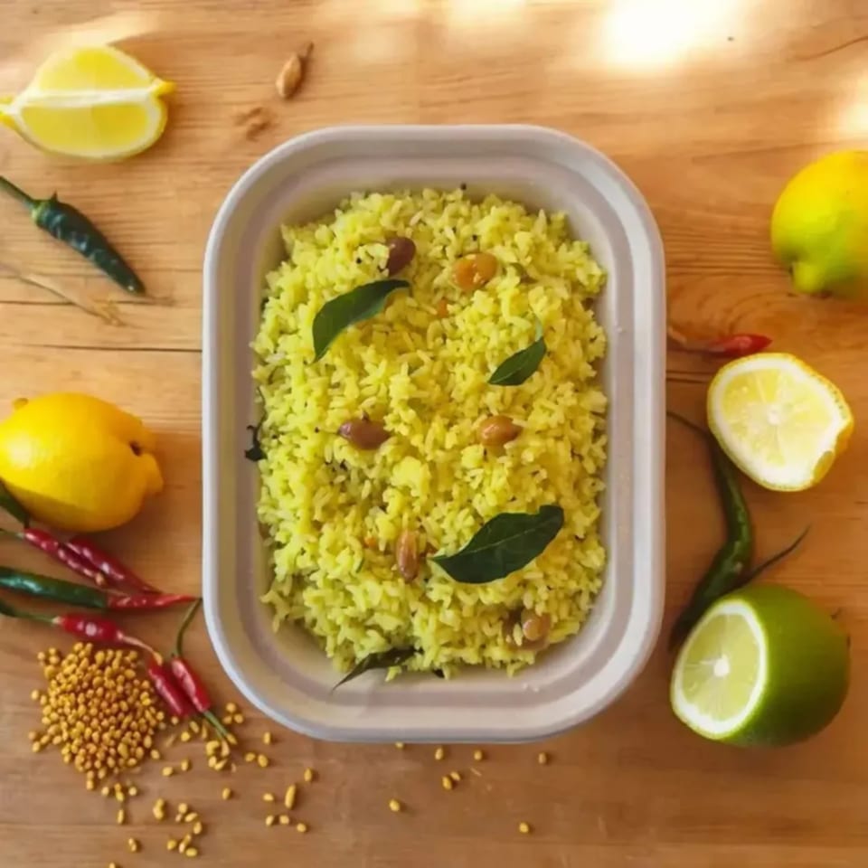 Bright yellow lemon rice with peanuts and curry leaves, surrounded by lemons, limes, and chilies.