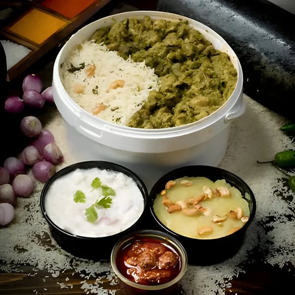 A large container of rice and green curry, with smaller bowls of yogurt, dessert, and chutney.