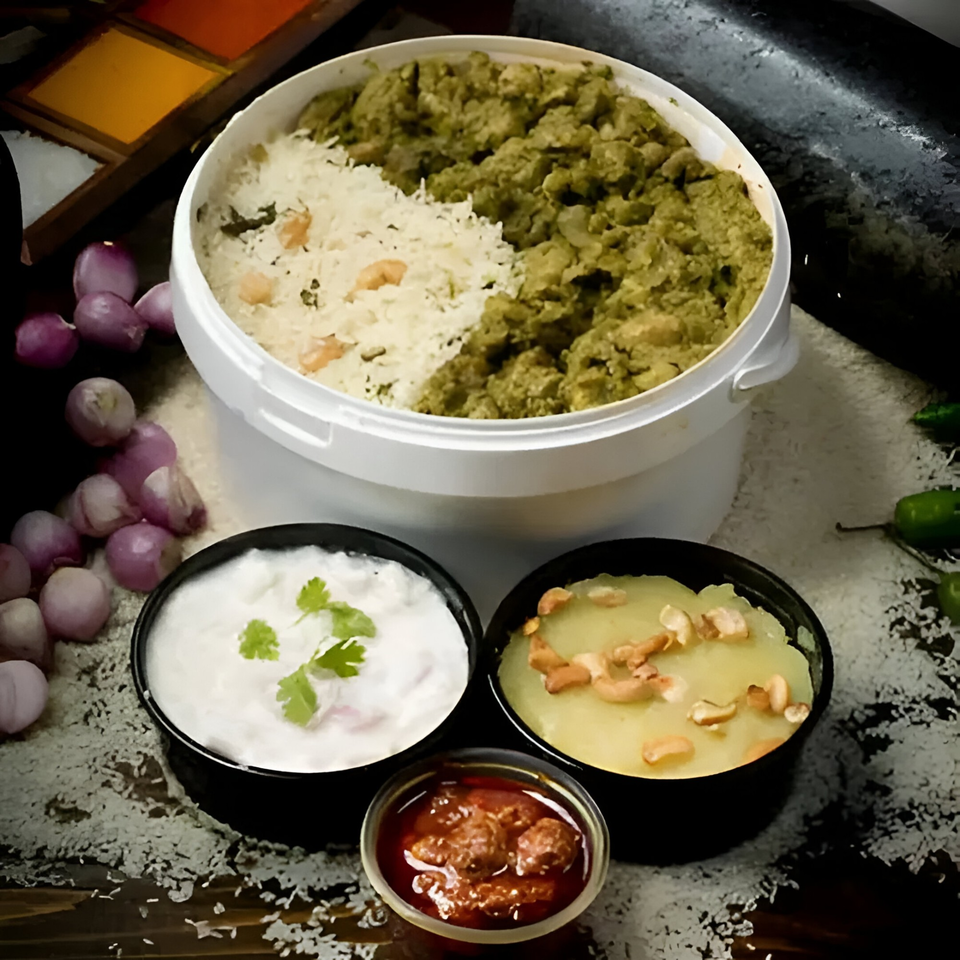 A large container of rice and green curry, with smaller bowls of yogurt, dessert, and chutney.
